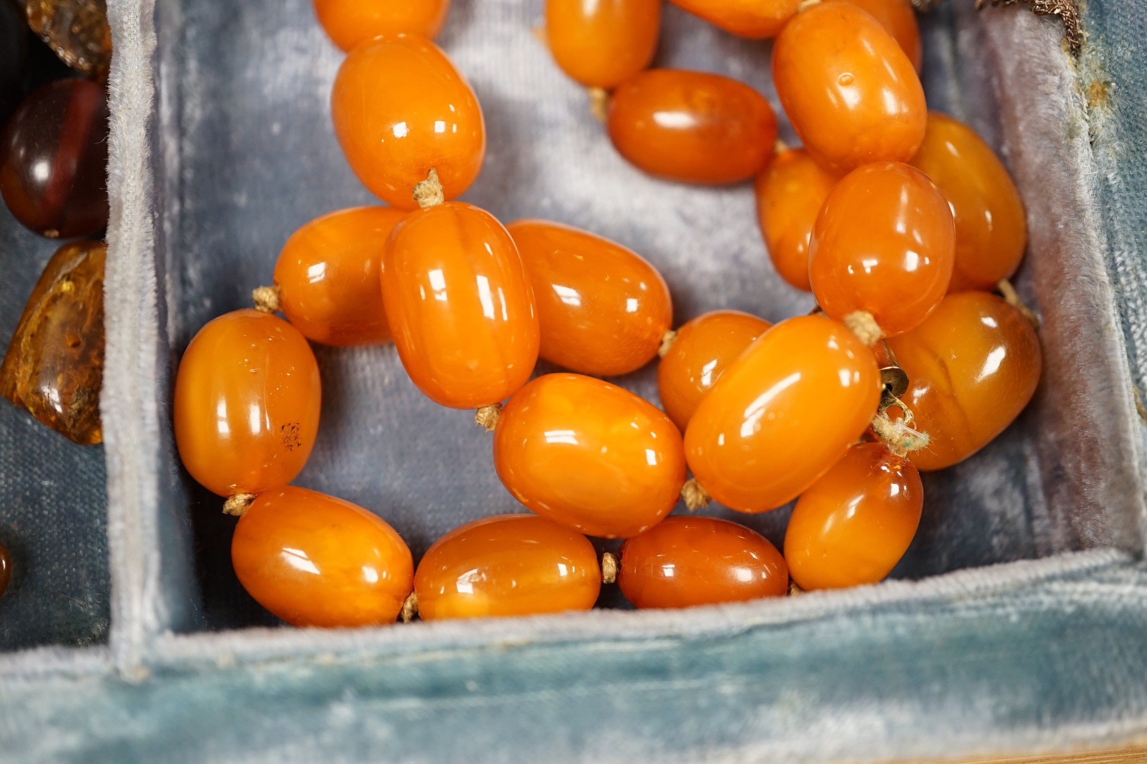 A single strand amber bead necklace, 48cm, gross 52 grams, together with other loose amber and amberoid beads and an amber pendant in a simulated book box.